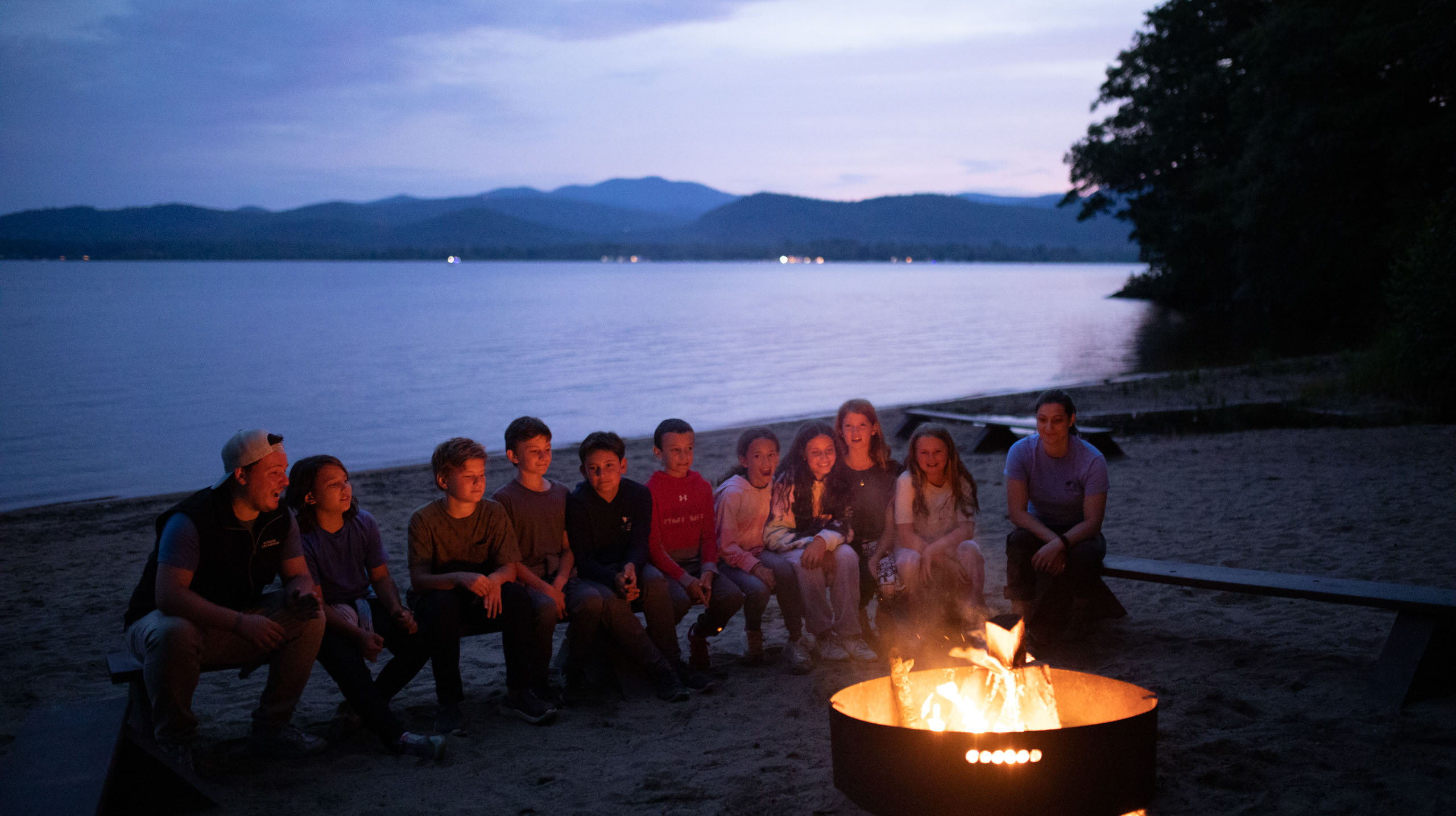 Kids sitting by campfire.